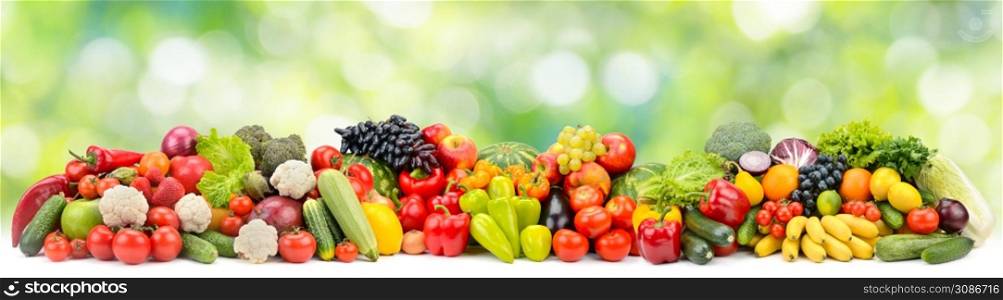 Panoramic photo multi-colored fruits and vegetables on green blurred background