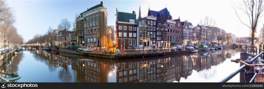 Panoramic scenic view of the city embankment and facades of houses at sunset. Amsterdam. Netherlands.. Panorama of the city waterfront of Amsterdam at sunset.
