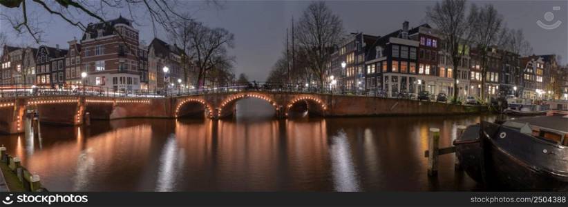 Panoramic scenic view of the city embankment and facades of houses at sunset. Amsterdam. Netherlands.. Panorama of the city waterfront of Amsterdam at sunset.