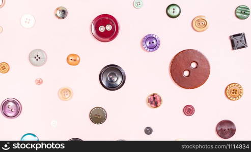 panoramic sewing background - top view of various buttons arranged on pink paper