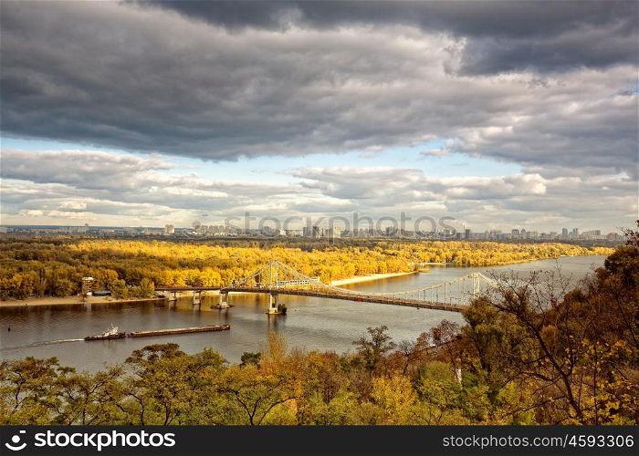 Panoramic urban landscape with river and bridge, seasonal view
