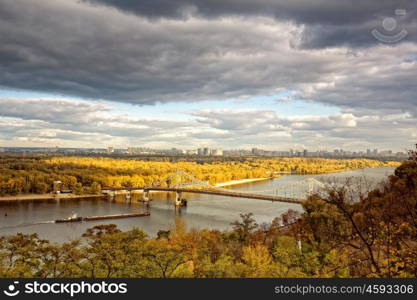 Panoramic urban landscape with river and bridge, seasonal view