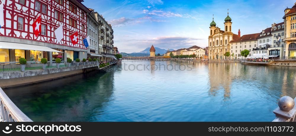 Panoramic view facades of old medieval houses on the city embankment at sunrise. Lucerne. Switzerland.. Lucerne. Old city embankment and medieval houses at dawn.