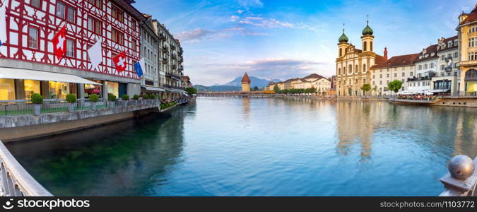 Panoramic view facades of old medieval houses on the city embankment at sunrise. Lucerne. Switzerland.. Lucerne. Old city embankment and medieval houses at dawn.