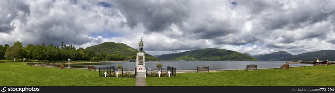 Panoramic view from Inveraray of Loch Fyne and war memorial with boat moored in harbour and hills in background