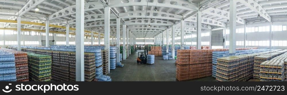 panoramic view of a large warehouse with drinks in plastic bottles with loading machines. large warehouse with drinks