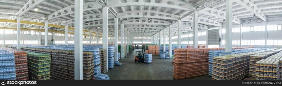 panoramic view of a large warehouse with drinks in plastic bottles with loading machines. large warehouse with drinks