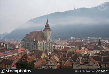 Panoramic view of Brasov old town and Black Church with the Carpathian Mountains in a foggy winter day. Transylvania, Romania. Brasov old town, Romania. Brasov old town, Romania