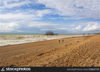 Panoramic view of Brighton&rsquo;s beach. In the background they are the remains of Brighton West Pier in sea. UK.. Panoramic view of Brighton&rsquo;s beach. In the background they are the remains of Brighton West Pier in sea.