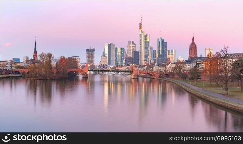 Panoramic view of business district with skyscrapers and mirror reflections in the river at pink sunrise, Frankfurt am Main, Germany. Frankfurt am Main in the morning, Germany