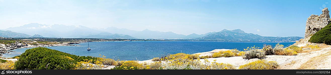 panoramic view of castle ruin in Corsica with mountains and sea in background