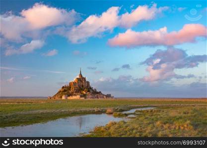 Panoramic view of famous Mont Saint Michel at sunset with reflection in the canal on the water meadows, Normandy, France. Mont Saint Michel at sunset, Normandy, France