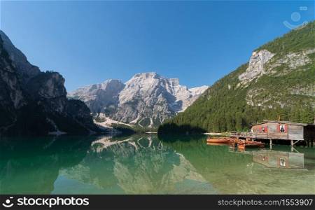 Panoramic view of Lake Braies and Seekofel mountain reflected in the water with a hut for boat rental