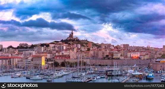 Panoramic view of Old Port and the Basilica of Notre Dame de la Garde on the background on the hill at sunset, Marseille, France. Old Port and Notre Dame, Marseille, France