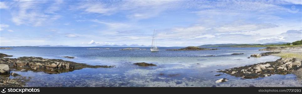 Panoramic view of sailing boat moored in clear water at Ronachan Point, Kintyre off the West coast of Scotland