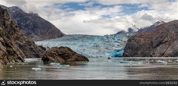 Panoramic view of Sawyer Glacier with a boat anchored by it in Alaska's Tracy Arm Fjords Terror Wilderness