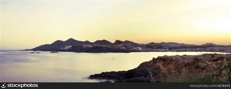 Panoramic view of sun setting over horizon at cabo de palos seascape in Murcia, Spain.. Panoramic view of sun setting over horizon at cabo de palos seascape in Murcia, Spain