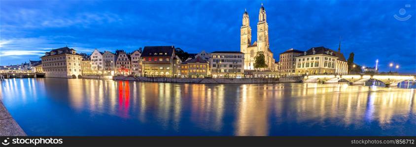 Panoramic view of the church Grossmunsterr and the city embankment in night-time lighting. Zurich. Switzerland.. Zurich. Panoramic view of the city embankment and the church Grossmunster at sunset.