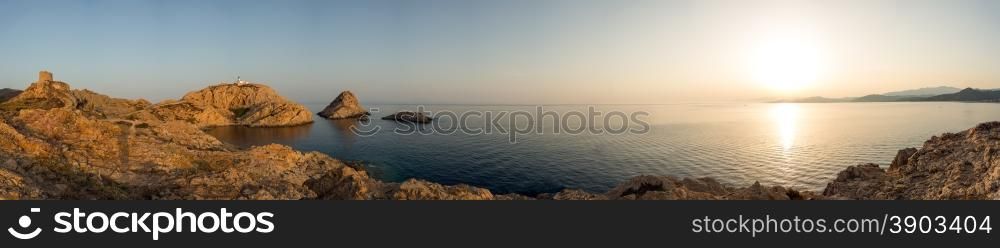 Panoramic view of the Genoese tower and lighthouse on the red rock at Ile Rousse in the Balagne region of Corsica with a calm mediterranean sea and desert des agriates in the distance