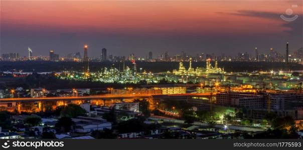Panoramic view of the oil refinery. The backdrop is a skyscraper business district. Twilight time. Panorama view of oil refinery factory