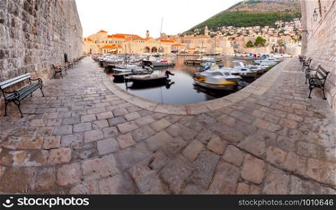 Panoramic view of the old harbor with fishing boats and the promenade in the early morning. Dubrovnik. Croatia.. Panorama of the old harbor and the city Dubrovnik in the morning.