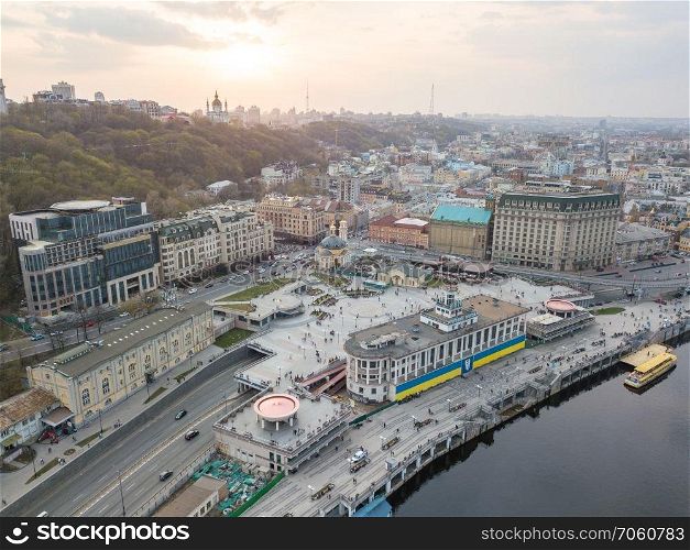 Panoramic view of the river station with walking ferries. Postal square, St. Andrew&rsquo;s Church and a television tower in the distance at sunset on Podol in Kiev, Ukraine. Photo from the drone. Panoramic view of the river station and Postal square at the sunset in Podil in Kiev, Ukraine