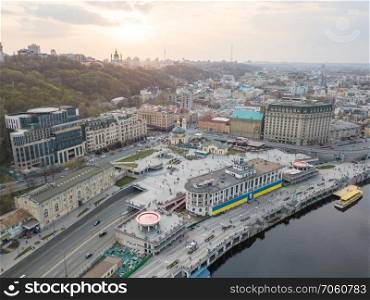 Panoramic view of the river station with walking ferries. Postal square, St. Andrew&rsquo;s Church and a television tower in the distance at sunset on Podol in Kiev, Ukraine. Photo from the drone. Panoramic view of the river station and Postal square at the sunset in Podil in Kiev, Ukraine
