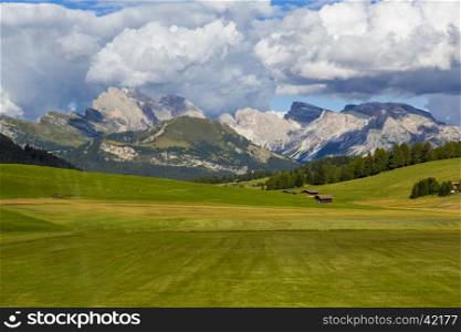 panoramic view of the Seiser Alm in a sunny day with blue sky and clouds with mountain range in the background