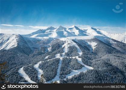 Panoramic view of the ski resort. Ski slopes and lifts passing through the forest