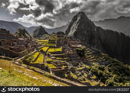 Panoramic view to old Inca ruins and Wayna Picchu with grey clouds in the background, Machu Picchu archaeological site, Urubamba provnce, Peru