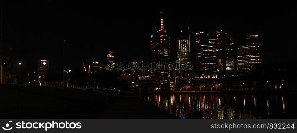 panoramic views of central Melbourne CBD building skyscrapers by the Yarra river at night time reflecting the city lights