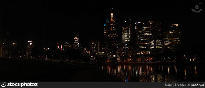 panoramic views of central Melbourne CBD building skyscrapers by the Yarra river at night time reflecting the city lights