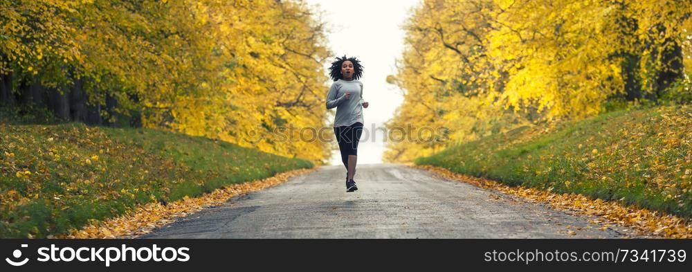 Panoramic web banner beautiful mixed race African American young woman girl teenager fitness running jogging in Autumn Fall trees