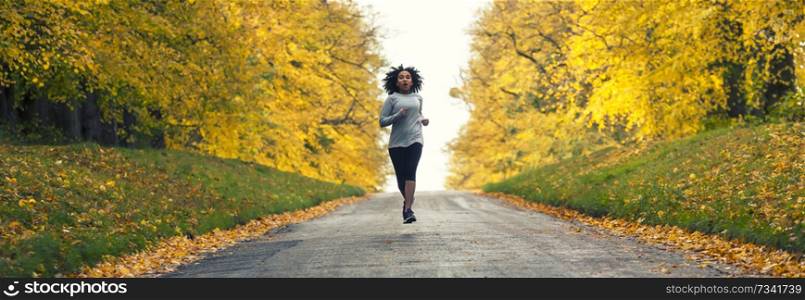 Panoramic web banner beautiful mixed race African American young woman girl teenager fitness running jogging in Autumn Fall trees