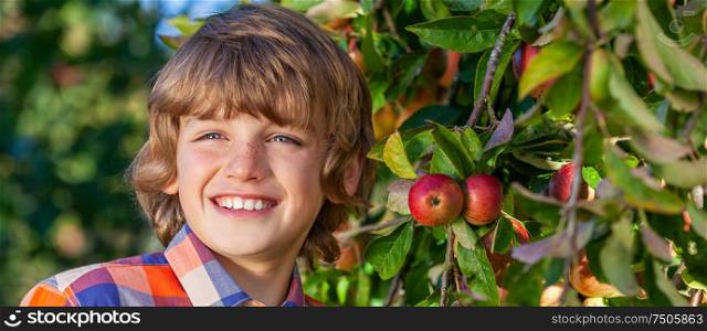 Panoramic web banner of happy smiling male boy child outdoors in an apple orchard panorama