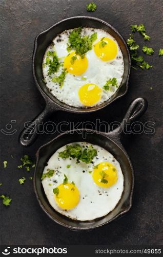 Pans with fried eggs and herbs on old metal background, top view. Food. Breakfast. Healthy food.