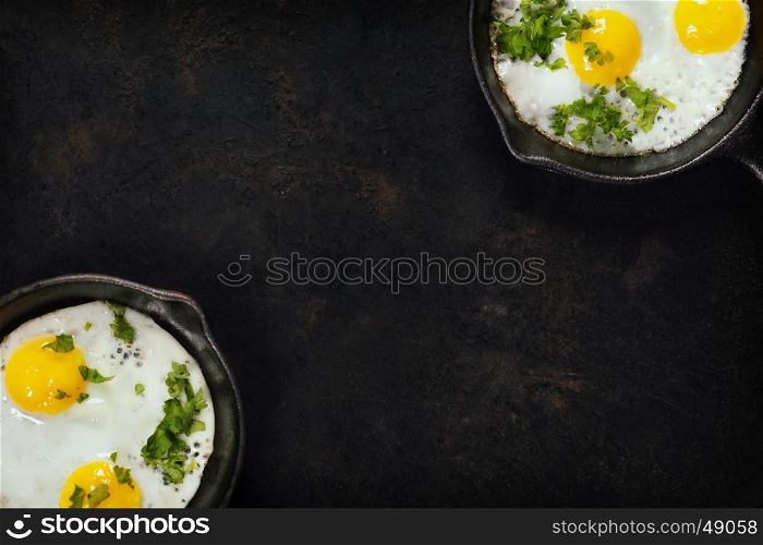 Pans with fried eggs and herbs on old metal background, top view. Food. Breakfast. Healthy food.