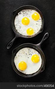 Pans with fried eggs on old metal background, top view. Food. Breakfast. Healthy food.