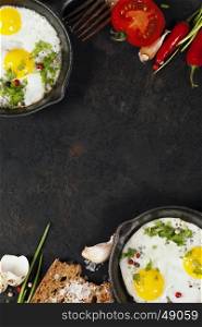Pans with fried eggs, tomatoes and bread on old metal background, top view. Food. Breakfast. Healthy food.