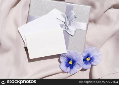 Pansy flowers and silk styled stock scene, for wedding invitation, product showcase or styled presentation with copy space, top view. Pansy flowers styled stock scene