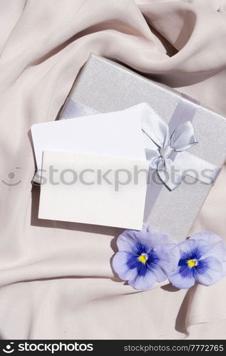 Pansy flowers and silk styled stock scene, for wedding invitation, product showcase or styled presentation with copy space, top view. Pansy flowers styled stock scene