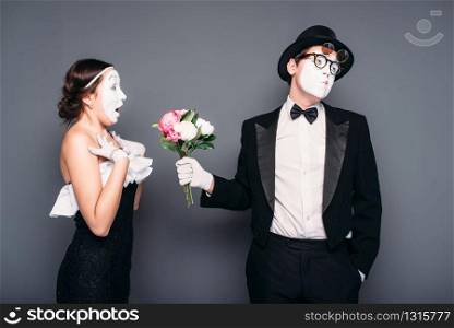 Pantomime actor and actress performing with flower bouquet. Mime theater performers posing. Comedy artists. Pantomime actors performing with flower bouquet