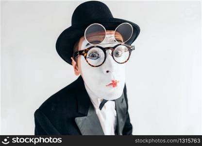 Pantomime actor face in glasses and makeup mask. Mime in suit, gloves and hat. April fools day concept
