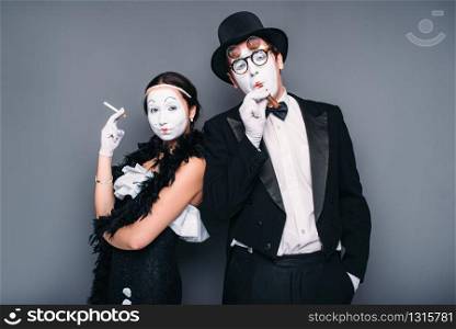Pantomime actors posing with cigar and cigarette. Comedy artist and actress performing. Mime theater performers