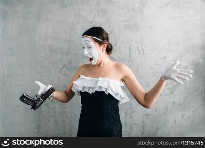 Pantomime theater actress performing with pistol. Comedian performer. Mime female artist with gun. April fools day concept