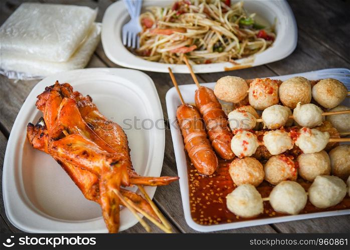 papaya salad grilled chicken wing and meat ball with sticky rice served on plate thai street food - selective focus