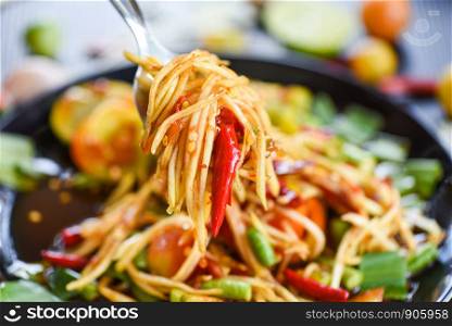 Papaya salad on a fork / Close up of green papaya salad spicy thai food on the table selective focus - Som tum Thai