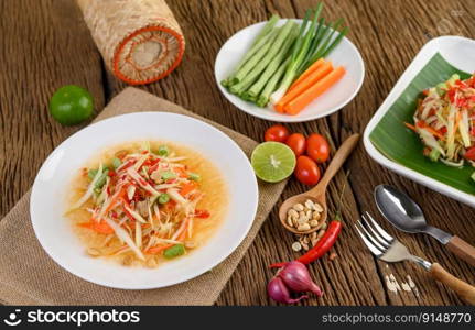 Papaya Salad  Som tum Thai  on a white plate on a wooden table.