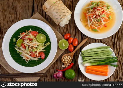 Papaya Salad (Som tum Thai) on a white plate on a wooden table.