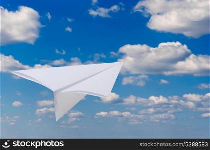 Paper airplane flying against blue sky and clouds